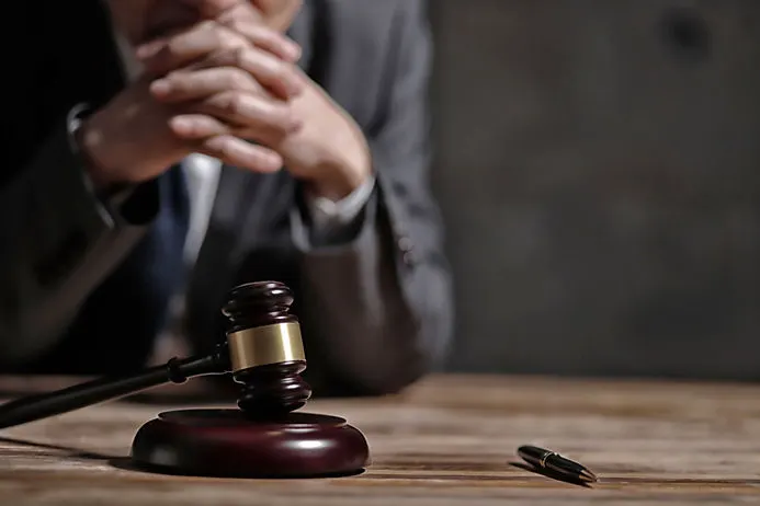 Martelo da justiça, e ao fundo homem de terno desfocado